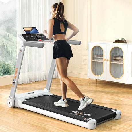 Woman using a treadmill in a home setting with a laptop on the console.